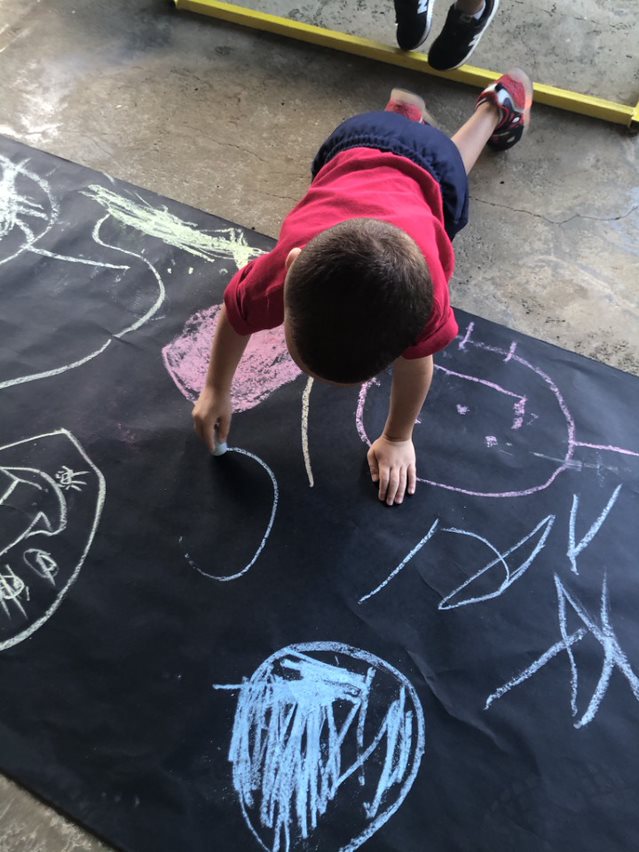 Imagen niño preescolar coloreando con tiza.