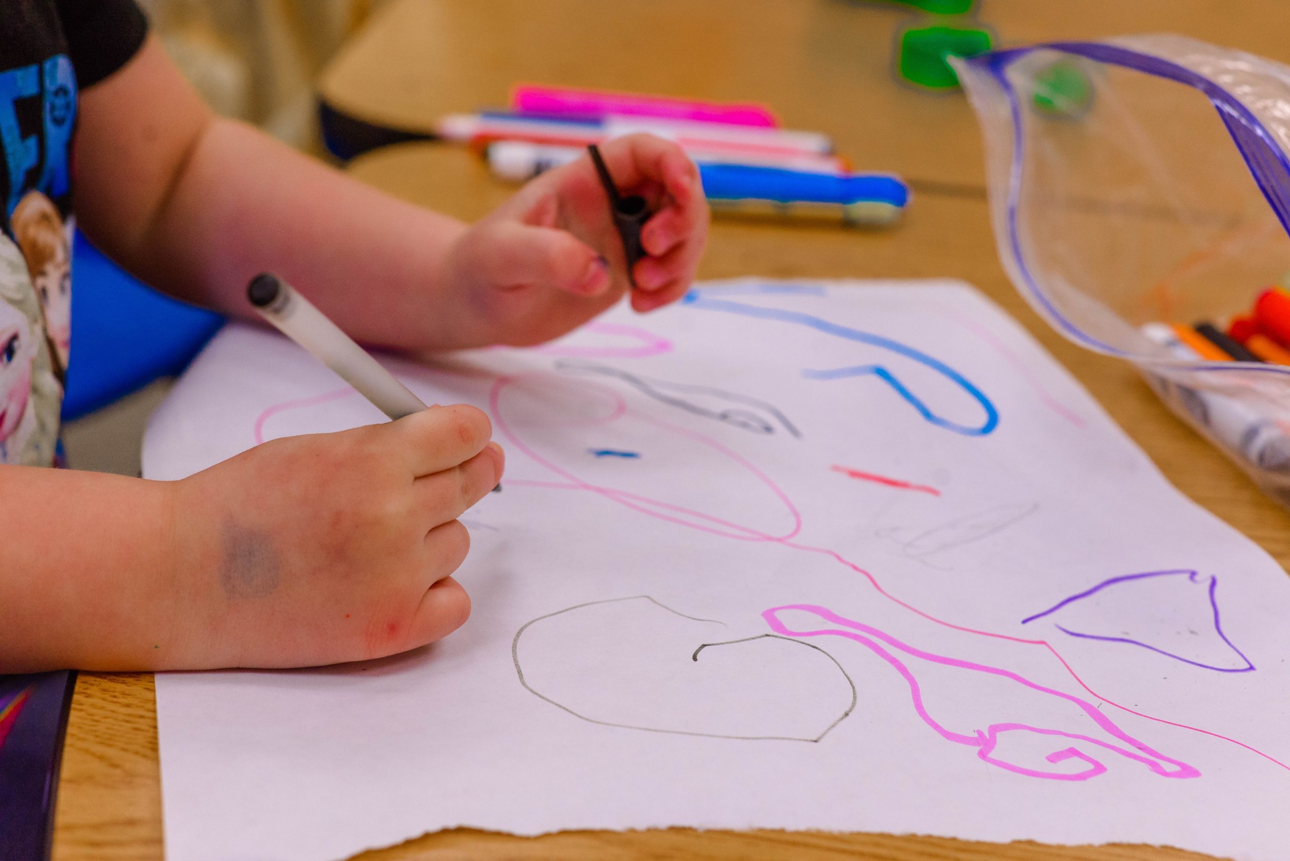 Imagen de las manos de un niño de escuela maternal dibujando con un marcador. Oprime sobre la imagen para obtener información de la Escuela Maternal.